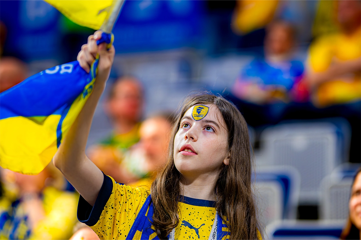 Ein Mädchen schwenkt mit einem Löwen Tattoo im Gesicht eine Löwen-Fahne
