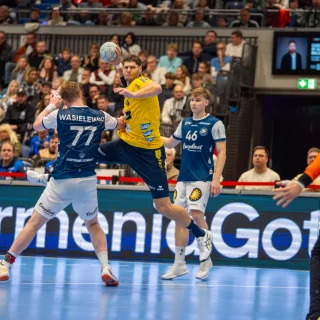 Basti Heymann in Wurfbewegung zwischen Außen- und Halbverteidiger